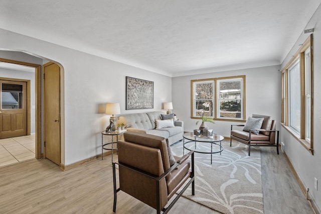 living room with baseboards, arched walkways, and light wood-style flooring