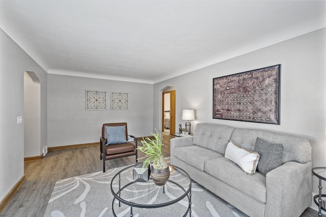 living room featuring baseboards, arched walkways, and wood finished floors