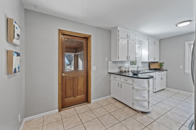 kitchen featuring backsplash, dark countertops, baseboards, light tile patterned flooring, and white cabinetry