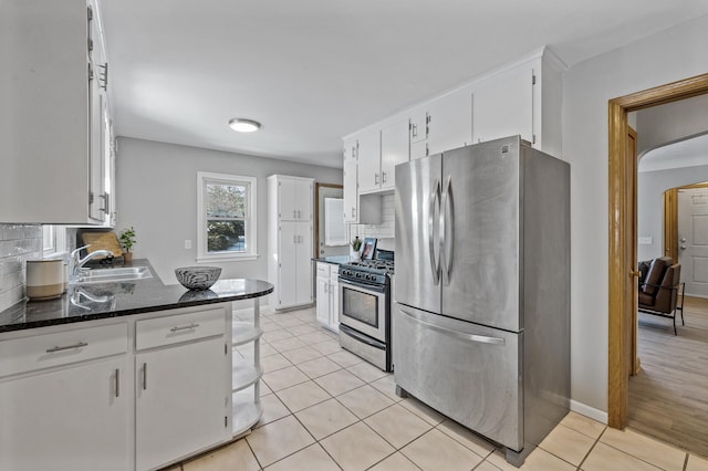 kitchen featuring backsplash, appliances with stainless steel finishes, a sink, light tile patterned flooring, and white cabinetry