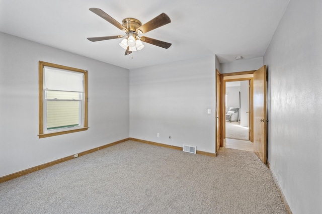 carpeted empty room featuring a ceiling fan, baseboards, and visible vents