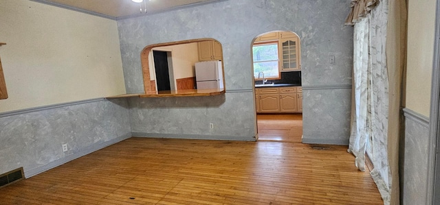 unfurnished room featuring ceiling fan, visible vents, crown molding, a sink, and light wood finished floors