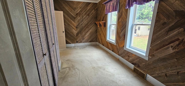 carpeted spare room with visible vents, wood walls, and baseboards