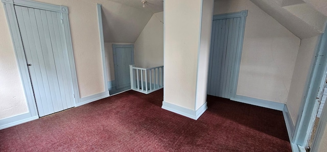 additional living space with dark colored carpet, baseboards, and vaulted ceiling
