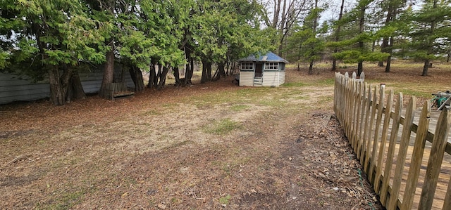 view of yard featuring a storage shed, fence, and an outdoor structure