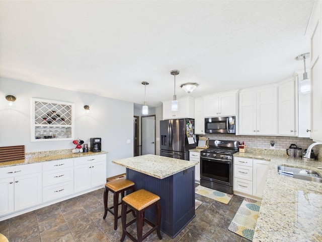 kitchen with stainless steel appliances, stone finish flooring, white cabinetry, and a sink
