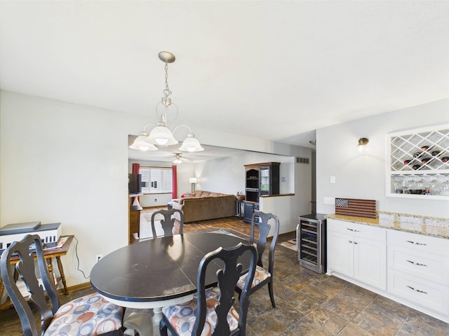 dining room with an inviting chandelier, stone finish flooring, baseboards, wine cooler, and indoor bar
