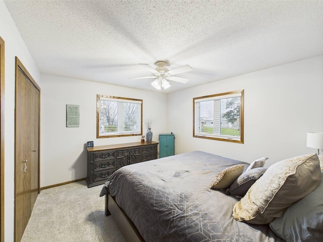 bedroom featuring multiple windows, light carpet, a closet, and a textured ceiling