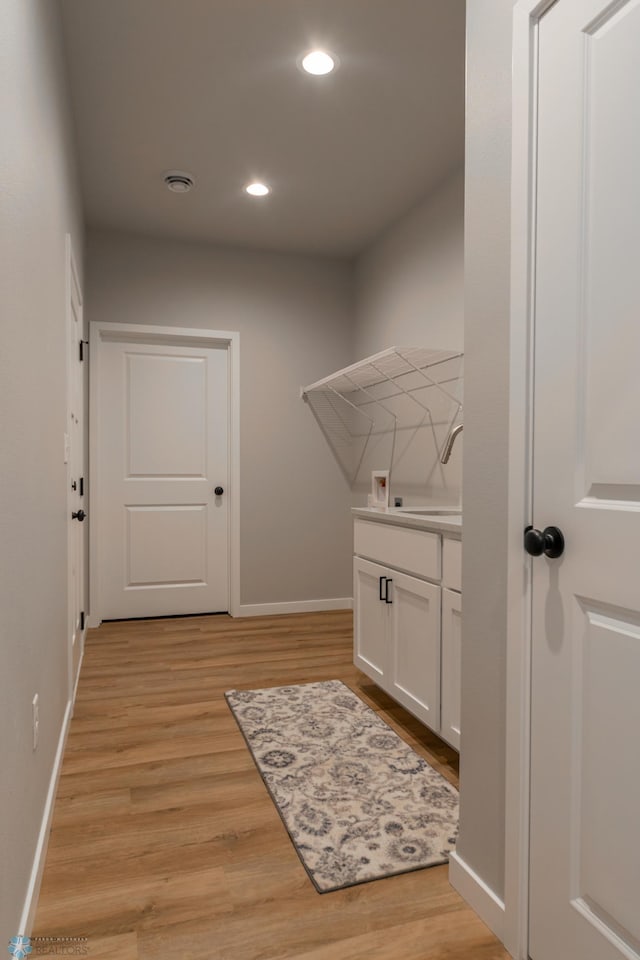 laundry area with a sink, baseboards, hookup for a washing machine, recessed lighting, and light wood-style flooring