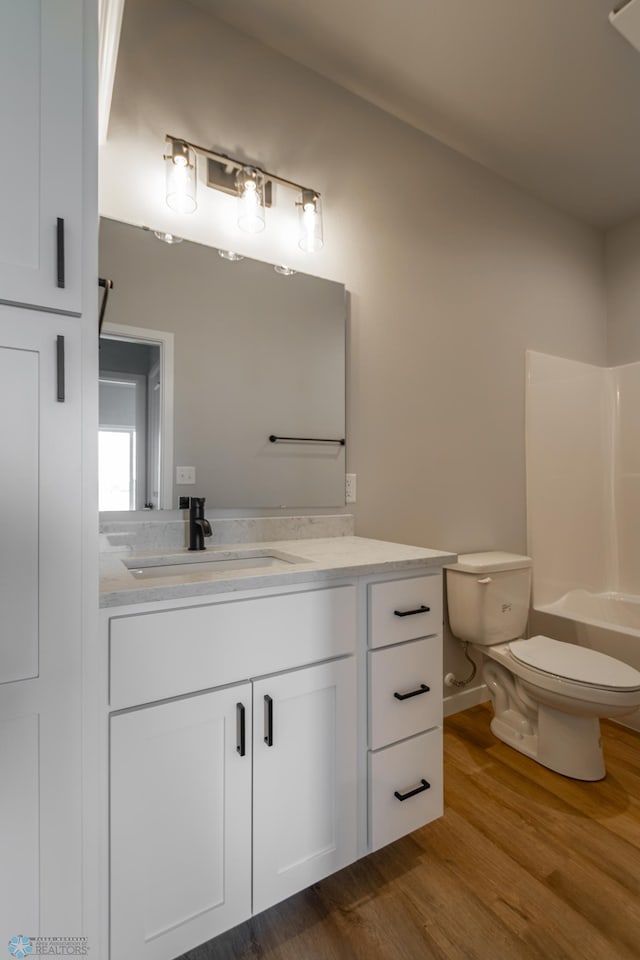 bathroom with vanity, toilet, wood finished floors, and tub / shower combination