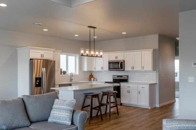 kitchen featuring white cabinetry, open floor plan, appliances with stainless steel finishes, and a sink