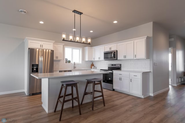 kitchen featuring a center island, decorative backsplash, white cabinetry, and stainless steel appliances