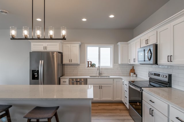 kitchen with a sink, appliances with stainless steel finishes, white cabinets, and backsplash