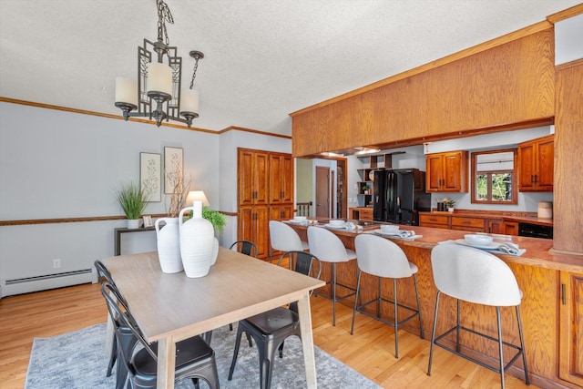 dining area with baseboard heating, light wood-style flooring, a chandelier, a textured ceiling, and ornamental molding