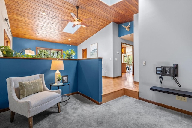sitting room featuring a skylight, wood ceiling, ceiling fan, baseboards, and carpet