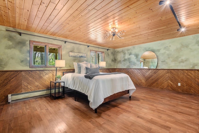 bedroom with a baseboard heating unit, wooden ceiling, multiple windows, a wainscoted wall, and wood walls