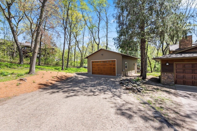 view of side of home featuring a garage, an outdoor structure, and a chimney