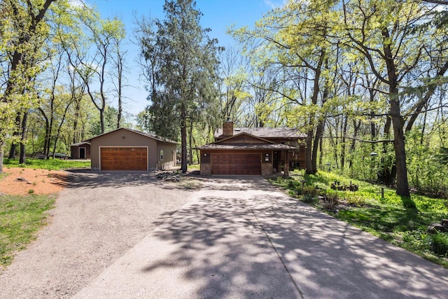 view of side of home with concrete driveway, a chimney, a garage, and an outdoor structure