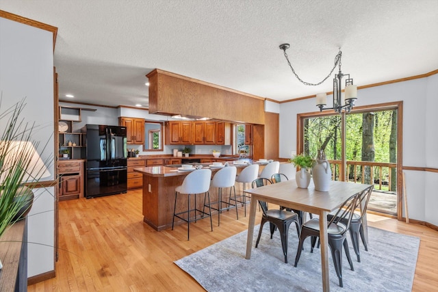 dining room featuring crown molding, a chandelier, light wood-type flooring, a textured ceiling, and recessed lighting