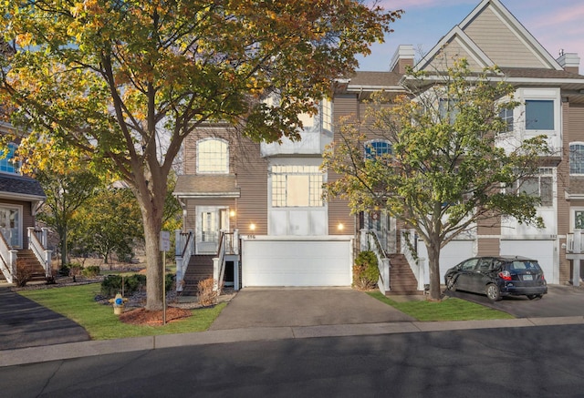 view of front of property with stairs, asphalt driveway, an attached garage, and a chimney