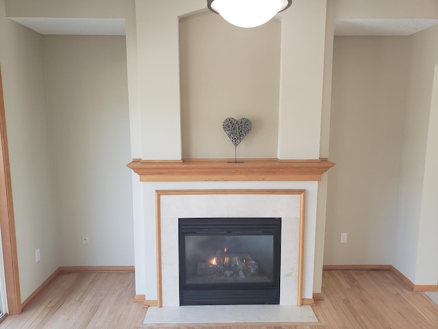 detailed view of wood finished floors, baseboards, and a fireplace with flush hearth