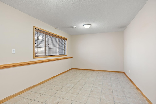 unfurnished room with a textured ceiling and baseboards