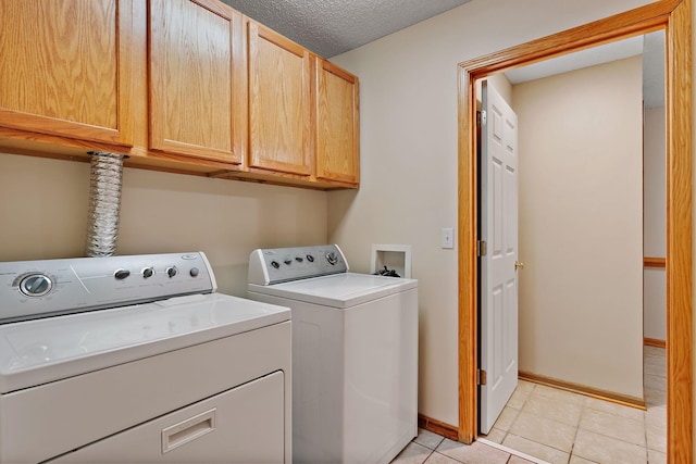 clothes washing area featuring washing machine and clothes dryer, cabinet space, light tile patterned floors, and baseboards
