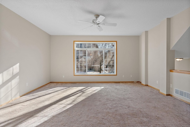 carpeted empty room featuring ceiling fan, baseboards, and a textured ceiling