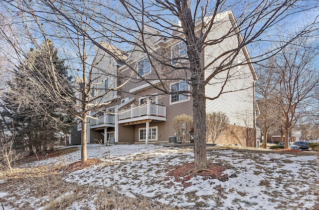 snow covered rear of property with central air condition unit and a wooden deck