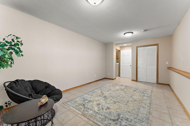 sitting room with light tile patterned floors, a textured ceiling, and baseboards