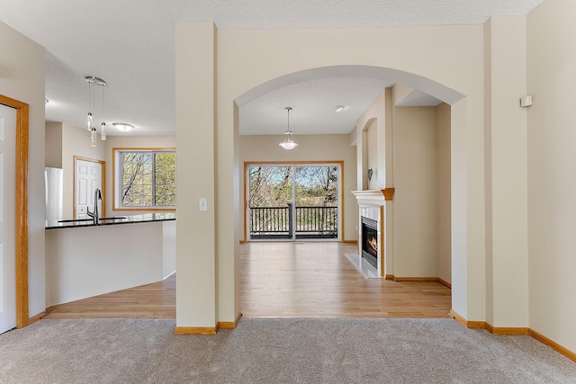 hallway with carpet, arched walkways, and a sink