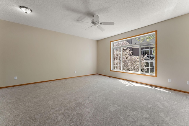 carpeted empty room with ceiling fan, baseboards, and a textured ceiling