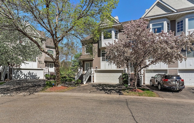 multi unit property with stairs, driveway, and a garage