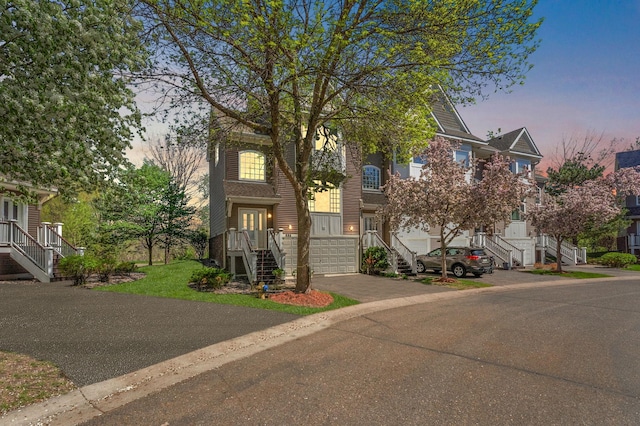 view of property featuring stairs, decorative driveway, and a garage
