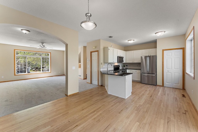 886 Trenton Ln N, Plymouth, MN 55441 - kitchen with stainless steel appliances, open floor plan, light wood-style flooring, dark countertops, and white cabinetry