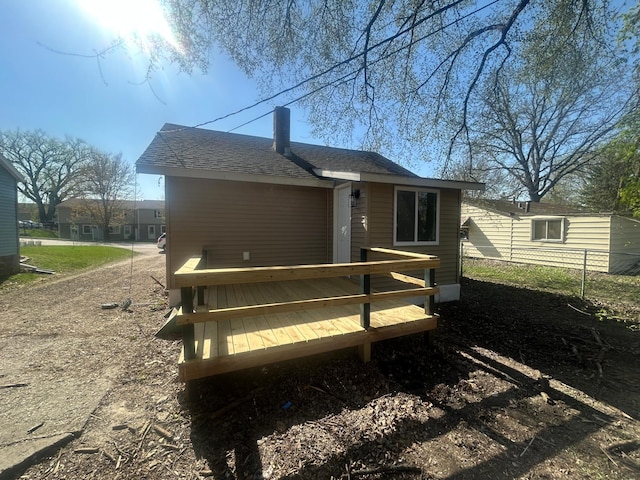 507 Peck St, Fergus Falls, MN 56537 - rear view of property featuring a wooden deck, a shingled roof, a chimney, and fence