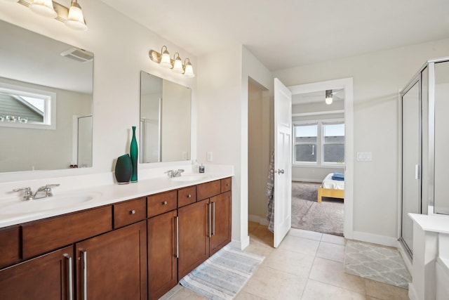 ensuite bathroom with a stall shower, double vanity, tile patterned flooring, and baseboards