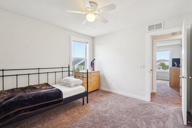 carpeted bedroom with multiple windows, baseboards, and ceiling fan