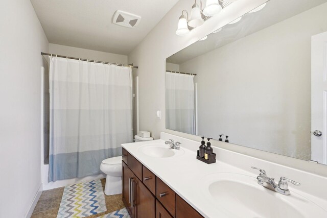 full bathroom featuring toilet, double vanity, and baseboards