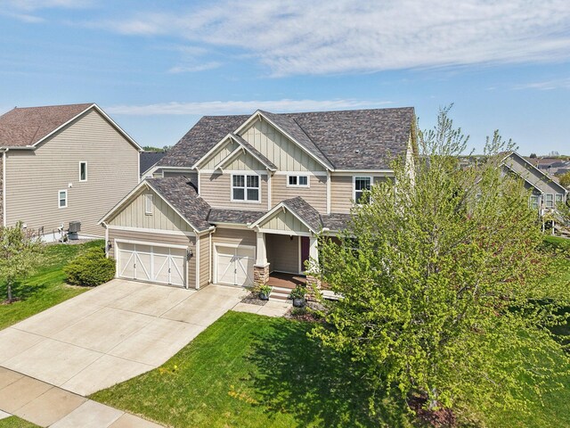 craftsman house with board and batten siding, concrete driveway, and a front yard