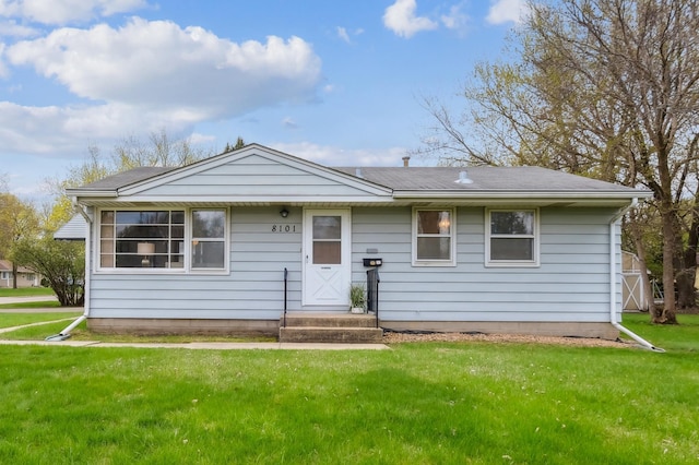 ranch-style home featuring a shingled roof and a front yard