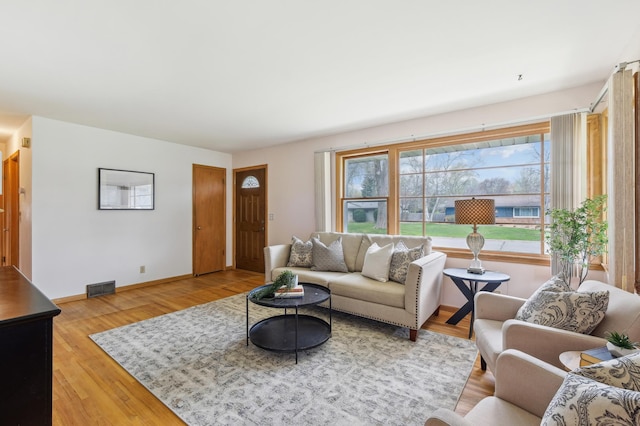 living area featuring baseboards, wood finished floors, and visible vents