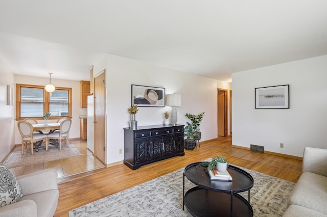 living room with baseboards, visible vents, and wood finished floors