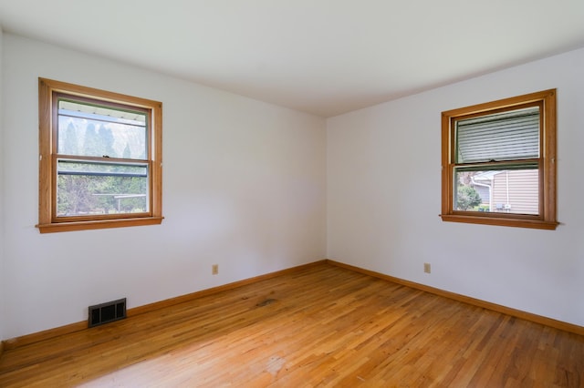 unfurnished room with baseboards, visible vents, and light wood-type flooring