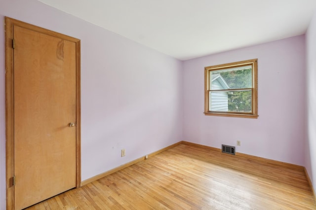 spare room featuring baseboards, light wood-style flooring, and visible vents