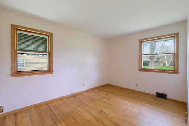 empty room featuring baseboards, visible vents, and light wood-style floors