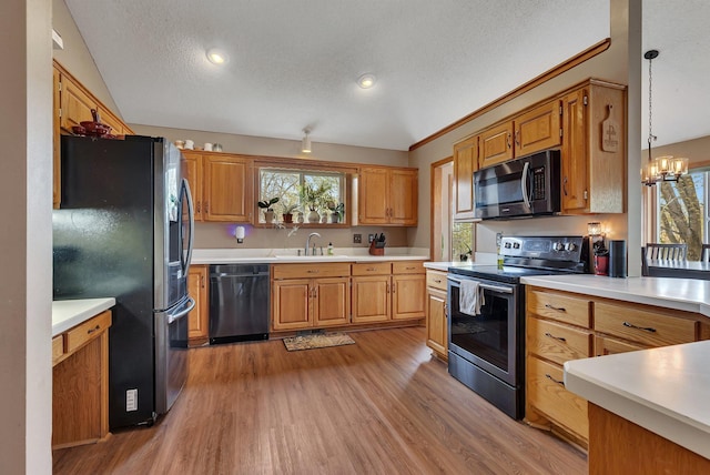 kitchen featuring appliances with stainless steel finishes, a sink, light countertops, a textured ceiling, and light wood-style flooring