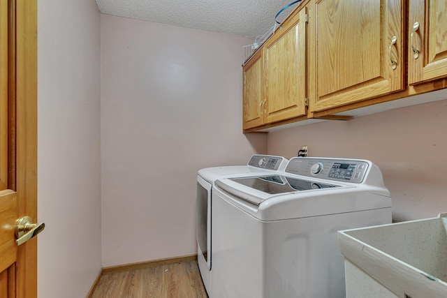 laundry room featuring independent washer and dryer, cabinet space, a sink, light wood-style flooring, and baseboards
