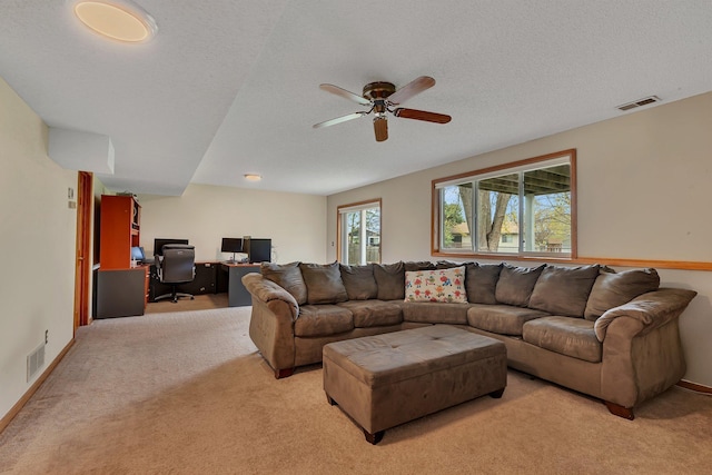 living room with visible vents, a textured ceiling, ceiling fan, and light colored carpet