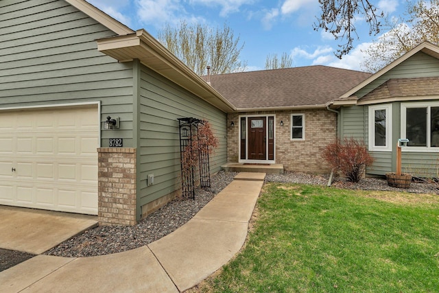 entrance to property with brick siding, an attached garage, roof with shingles, and a yard